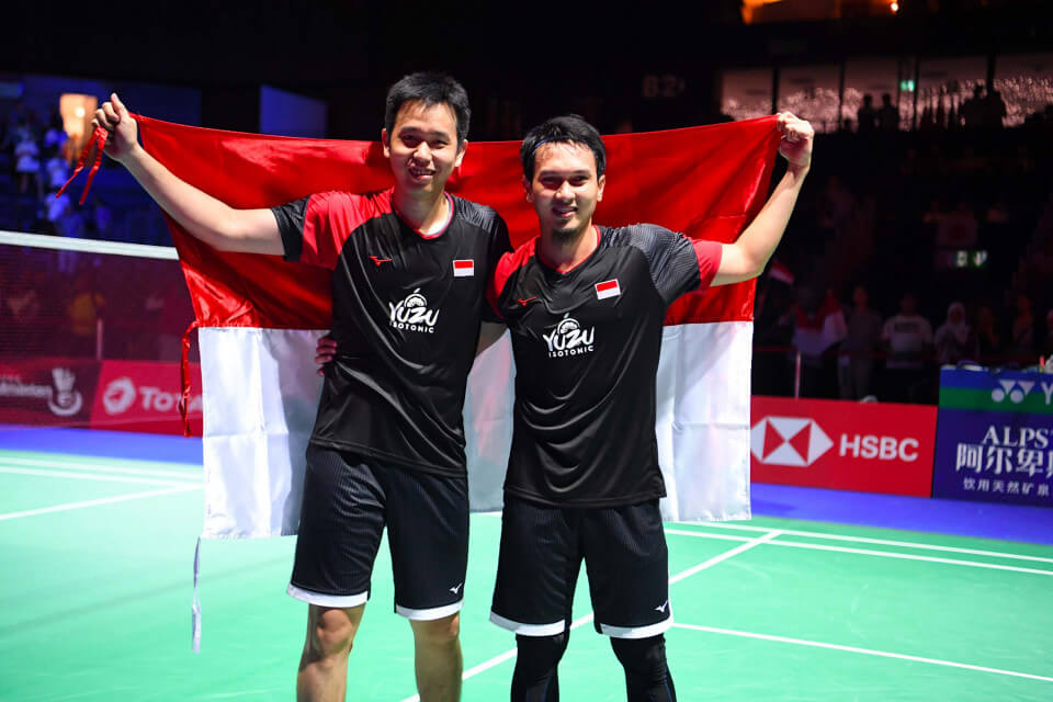 Hendra dan Ahsan berfoto dengan membawa bendera Indonesia.
